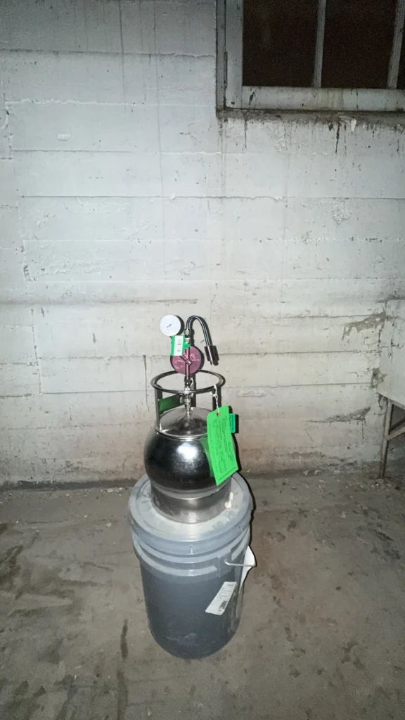 stainless steel Summa canister with a flow controller set up for indoor air and vapor intrusion testing in a building basement in Fayetteville, Arkansas.